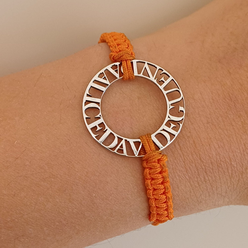 Immagina un cerchio liscio e leggero, con nomi traforati che emergono come piccole sculture tra il vuoto e la luce. Ogni lettera è incisa con precisione, creando un contrasto tra il metallo freddo e il calore del cordino intrecciato a mano, morbido e avvolgente sul polso. La superficie è liscia, con bordi definiti ma delicati al tatto. Questo bracciale personalizzato è un abbraccio in argento, con parole che parlano di affetti, ricordi e connessioni profonde.