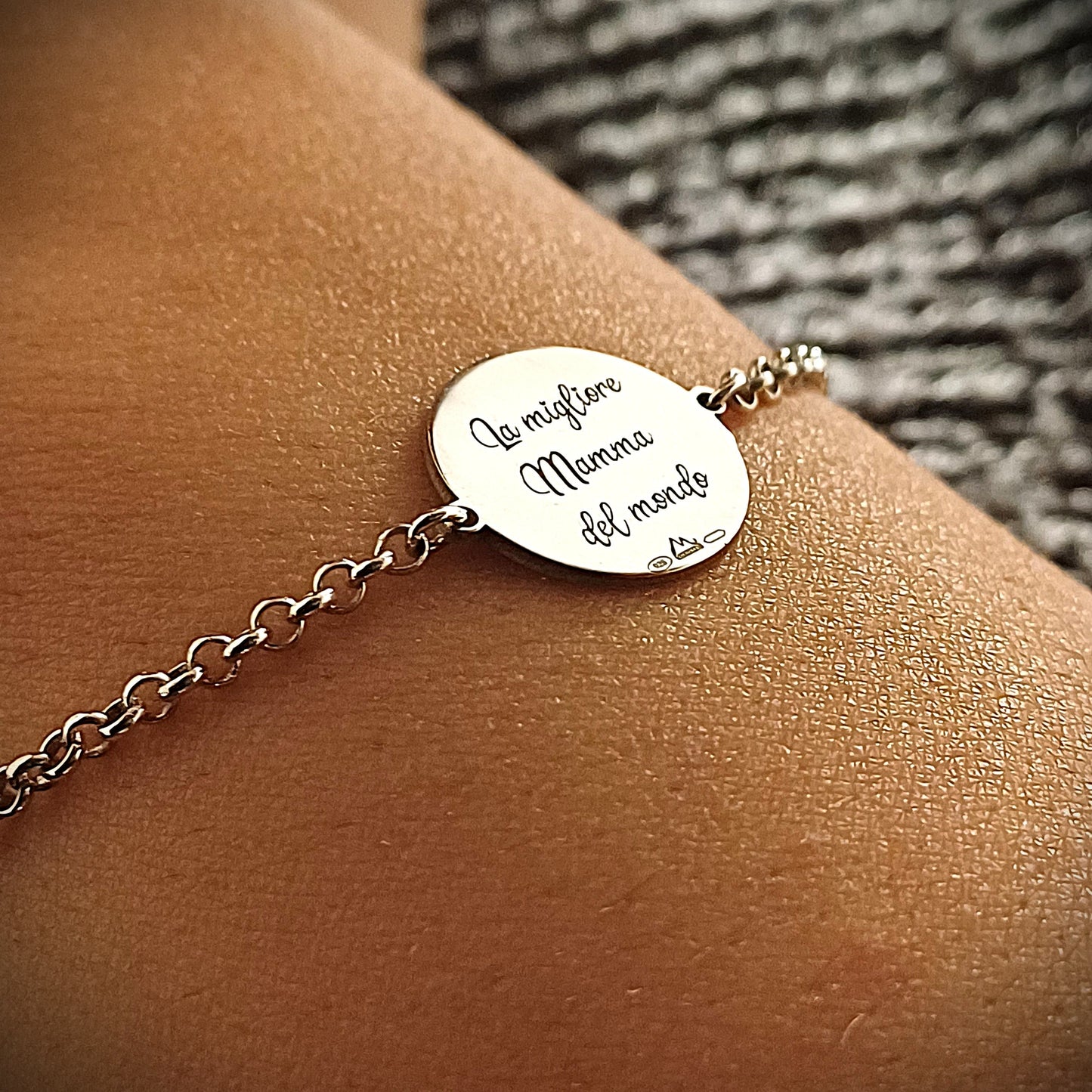 Bracciale in argento 925 con una catena sottile e morbida al polso.
Al centro, un medaglione rotondo piatto, spesso circa 1 mm, dal diametro di circa 2 cm.
È completamente liscio al tatto e molto lucido.
Sopra è incisa la frase “La migliore Mamma del mondo” in caratteri eleganti, percettibili al tatto ma non in rilievo forte.
Il bracciale è leggero, comodo da indossare ogni giorno, e trasmette un messaggio affettuoso.