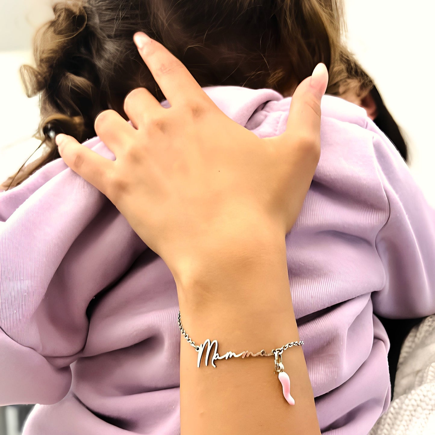 Bracciale sottile e leggero in argento 925, con catena a maglia fine e chiusura ad anello a molla. Al centro, una scritta liscia e lucida in corsivo: "Mamma", tagliata in un unico pezzo di metallo, con la lettera “M” leggermente più alta e curva. Il metallo è liscio al tatto, senza spigoli, con una finitura brillante. Il bracciale è morbido al polso e pensato per un uso quotidiano, leggero e confortevole.