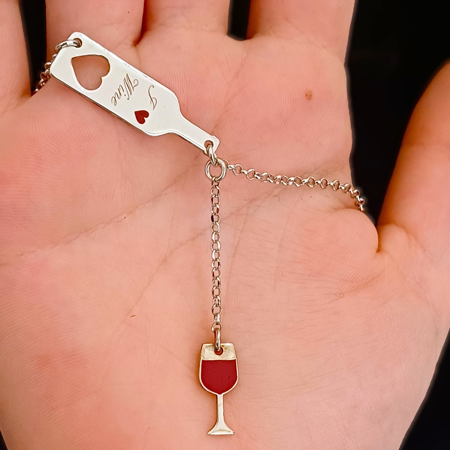 Questo girocollo in argento 925 è leggero e liscio al tatto, con due ciondoli dettagliati: una bottiglia slanciata e un bicchiere sottile. La scritta in rilievo "I Love Wine" si percepisce con le dita, dando un tocco di carattere al design. Il metallo è anallergico e piacevole sulla pelle. È possibile personalizzare il retro della bottiglia con un’incisione speciale, rendendolo un regalo unico per chi ama il vino e l’eleganza.