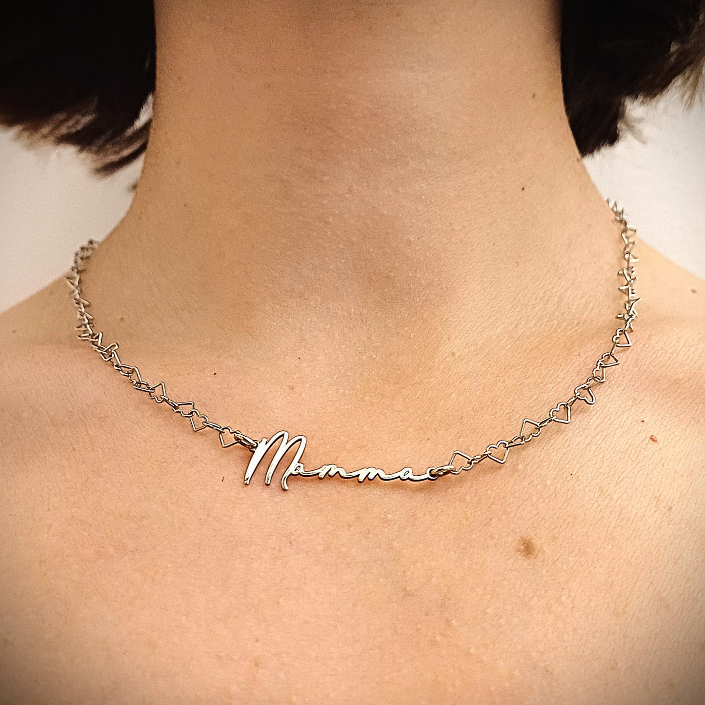 Un girocollo in argento 925 con una catena composta da tanti piccoli cuoricini vuoti, leggeri e delicati. Al centro, la parola “Mamma” è scritta in corsivo, con una linea sottile ma ben definita. L’intera collana è luminosa e leggera, pensata per rappresentare con dolcezza l’amore materno. Un gioiello elegante, semplice e affettuoso, perfetto da regalare per la Festa della Mamma o per ogni occasione speciale.