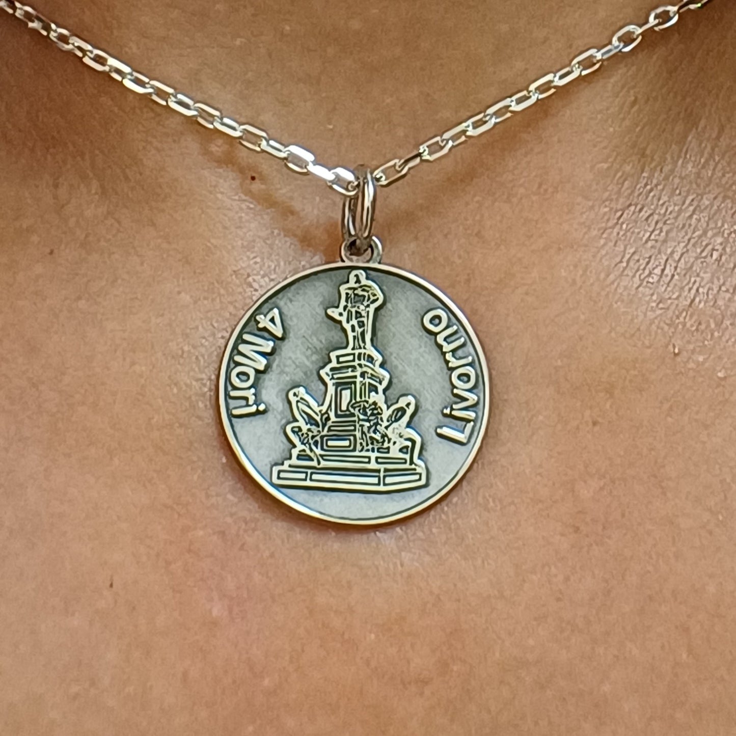 Un ciondolo rotondo in oro o argento 925 con un’incisione raffinata che raffigura i Quattro Mori, simbolo storico di Livorno. La superficie liscia e i dettagli scolpiti al laser donano al gioiello una bellezza unica. Realizzato artigianalmente nel nostro laboratorio orafo a Livorno, questo ciondolo è un pezzo che unisce tradizione e modernità. Perfetto per chi desidera portare con sé un frammento della storia della città, in un design elegante e significativo.