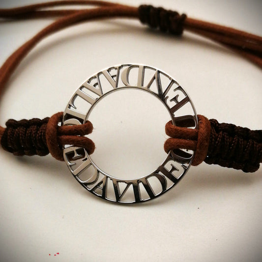 Immagina un cerchio liscio e leggero, con nomi traforati che emergono come piccole sculture tra il vuoto e la luce. Ogni lettera è incisa con precisione, creando un contrasto tra il metallo freddo e il calore del cordino intrecciato a mano, morbido e avvolgente sul polso. La superficie è liscia, con bordi definiti ma delicati al tatto. Questo bracciale personalizzato è un abbraccio in argento, con parole che parlano di affetti, ricordi e connessioni profonde.