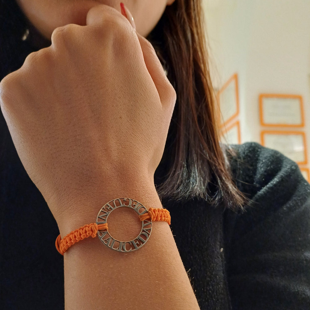 Immagina un cerchio liscio e leggero, con nomi traforati che emergono come piccole sculture tra il vuoto e la luce. Ogni lettera è incisa con precisione, creando un contrasto tra il metallo freddo e il calore del cordino intrecciato a mano, morbido e avvolgente sul polso. La superficie è liscia, con bordi definiti ma delicati al tatto. Questo bracciale personalizzato è un abbraccio in argento, con parole che parlano di affetti, ricordi e connessioni profonde.