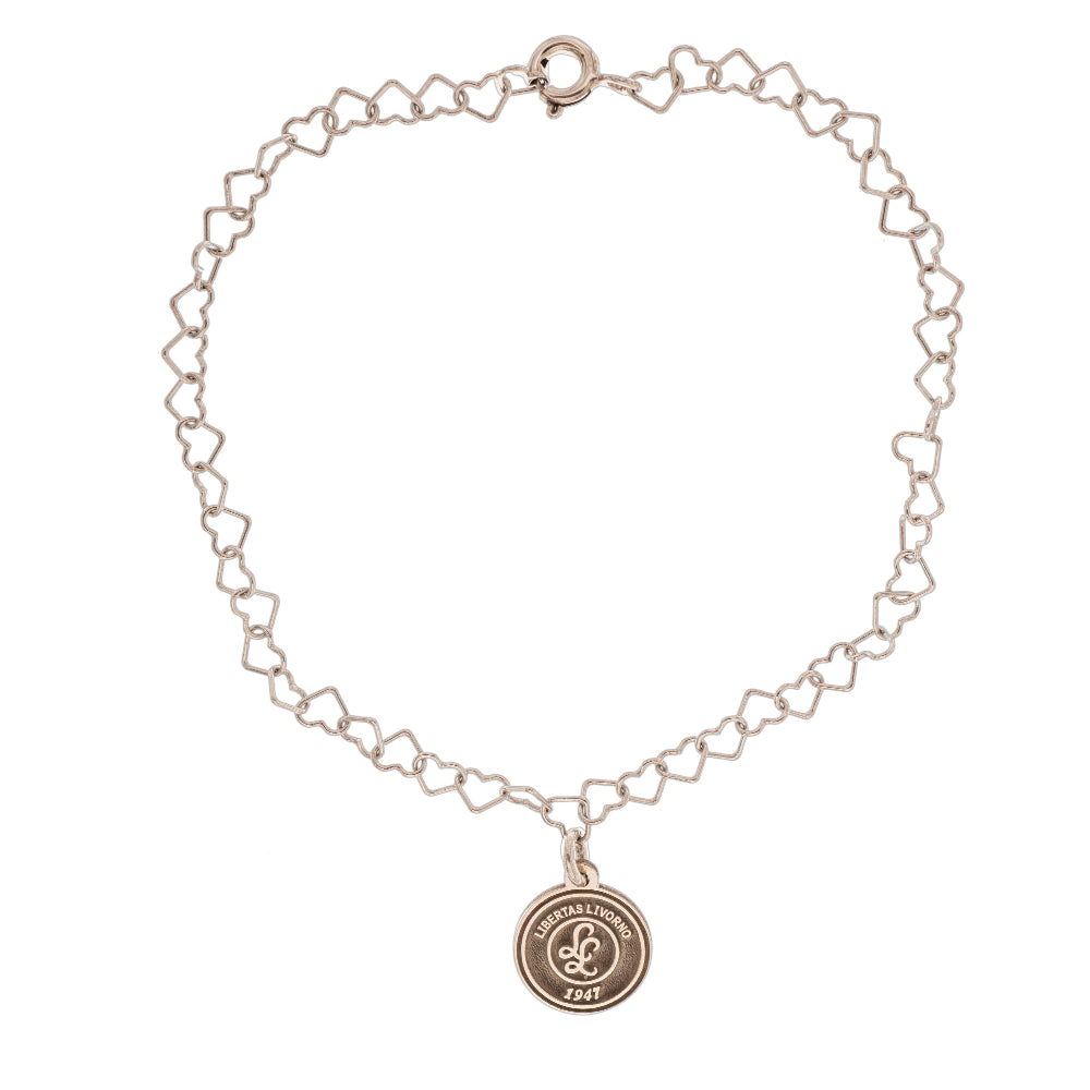 Questo braccialetto in argento 925 ha una catena di maglie a forma di cuore e una medaglietta rotonda da 10 mm. La superficie della medaglietta è lavorata artigianalmente nel nostro laboratorio orafo a Livorno e presenta il logo della Libertas Livorno 1947, inciso a laser e smaltato a caldo con un ricco colore amaranto. È un pezzo elegante e sportivo, pensato per celebrare la passione e l'appartenenza. Ideale per chi cerca gioielli personalizzati e distintivi.