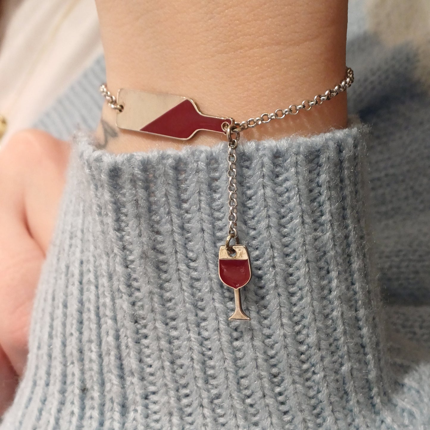  bracciale in argento con un design unico: una bottiglia di vino stilizzata lucida a cui è collegato un piccolo calice pendente. La catenina è sottile a maglie rolò con chiusura a moschettone regolabile, ideale per un look raffinato e originale. Perfetto per gli amanti del vino, questo gioiello aggiunge un tocco di stile e passione al polso. dettaglio indossata