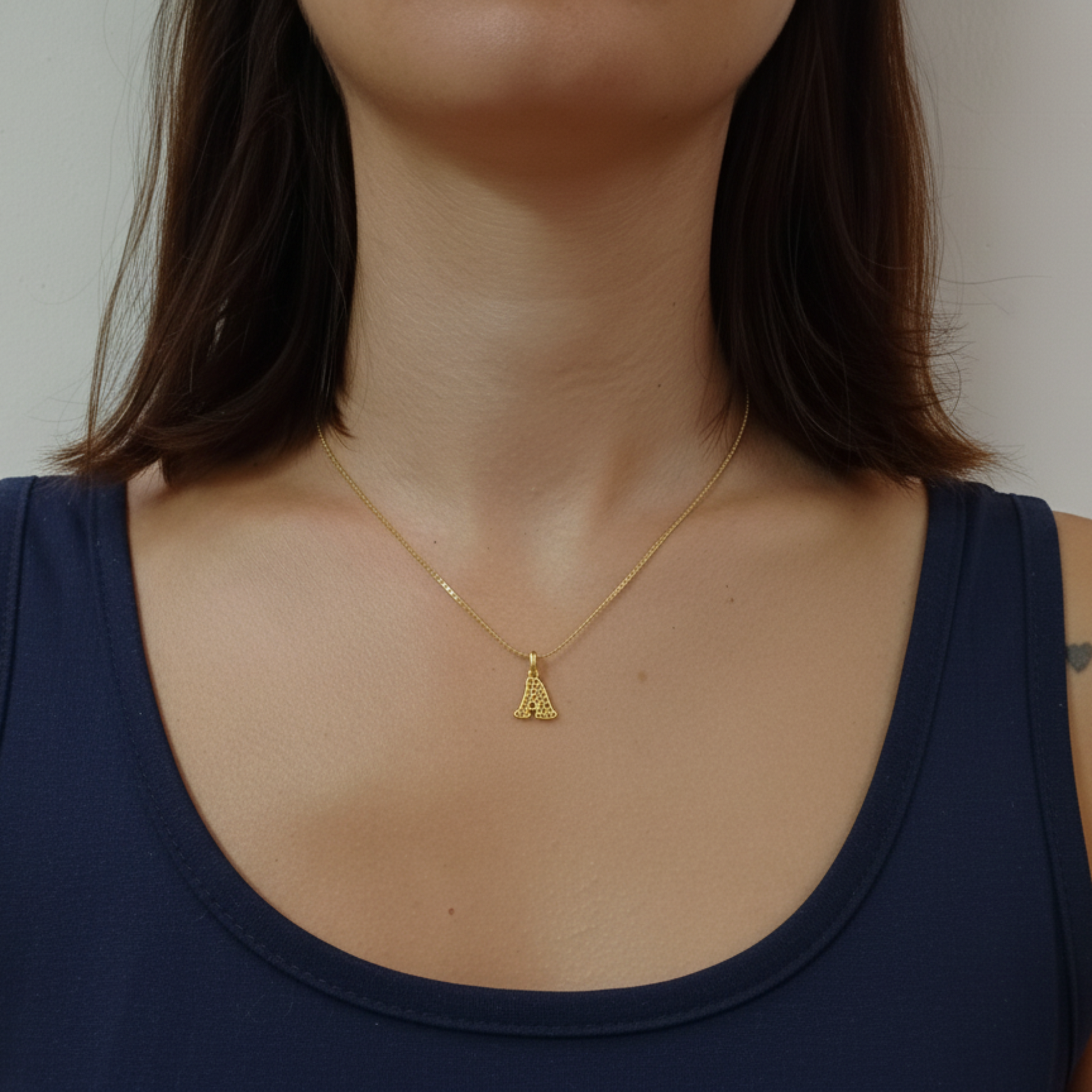 Ciondolo in oro a forma di lettera personalizzabile. Design traforato moderno e luminoso, prezzo 40 €.