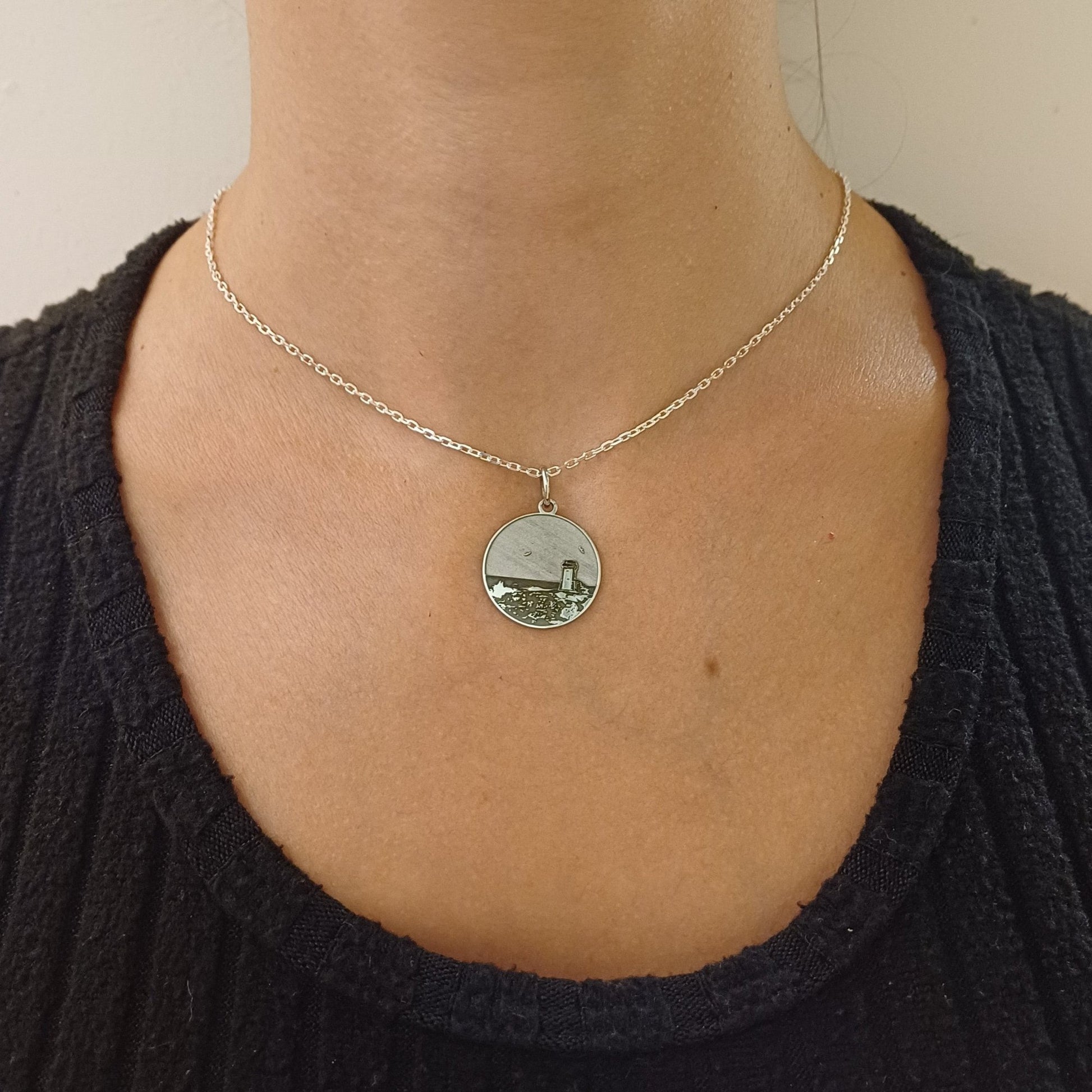 Questa è una medaglia in argento 925, rotonda e piatta, con un diametro di circa 20 mm. Sulla superficie è incisa la Torre di Calafuria, un faro storico situato sulla costa di Livorno. La torre è rappresentata in rilievo, con dettagli che mostrano il paesaggio circostante, come il mare e la scogliera. È un pezzo elegante e simbolico, pensato per celebrare un luogo iconico. La medaglia è dotata di un piccolo anello sulla parte superiore, che ne consente l'uso come ciondolo.