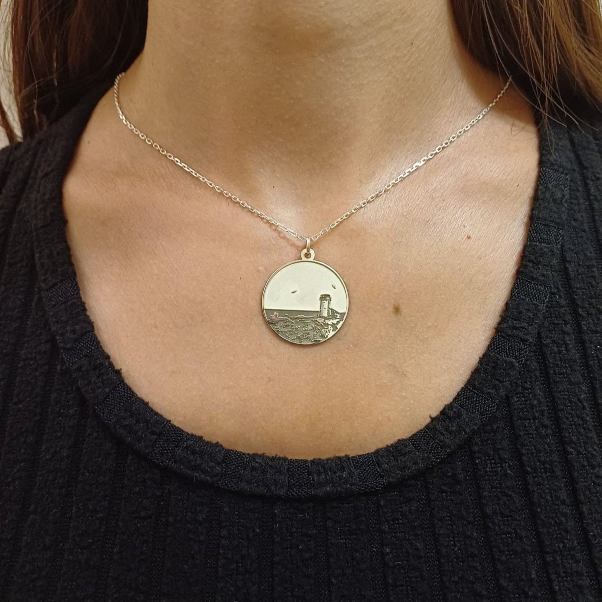 Questa è una medaglia in argento 925, rotonda e piatta, con un diametro di circa 20 mm. Sulla superficie è incisa la Torre di Calafuria, un faro storico situato sulla costa di Livorno. La torre è rappresentata in rilievo, con dettagli che mostrano il paesaggio circostante, come il mare e la scogliera. È un pezzo elegante e simbolico, pensato per celebrare un luogo iconico. La medaglia è dotata di un piccolo anello sulla parte superiore, che ne consente l'uso come ciondolo.