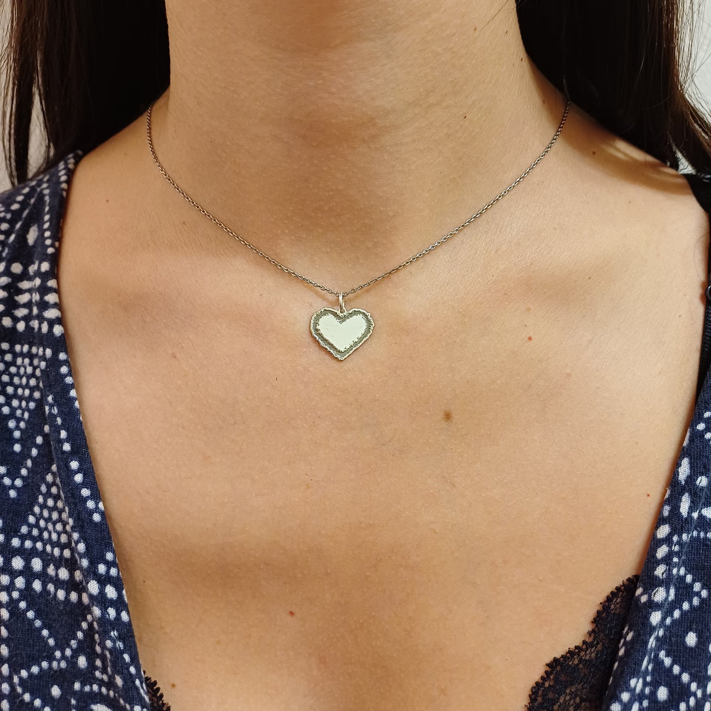 Questo ciondolo è a forma di cuore e realizzato in oro 18 carati. Ha un contorno frastagliato e irregolare, come disegnato a mano libera, con una superficie centrale liscia e morbida al tatto. La forma è piena e il bordo ha una texture ruvida, che lo rende unico e piacevole da accarezzare con le dita. È pensato per essere indossato o saldato su un gioiello, e rappresenta un sentimento puro e vero. Ogni pezzo è fatto a mano nel nostro laboratorio artigianale.
