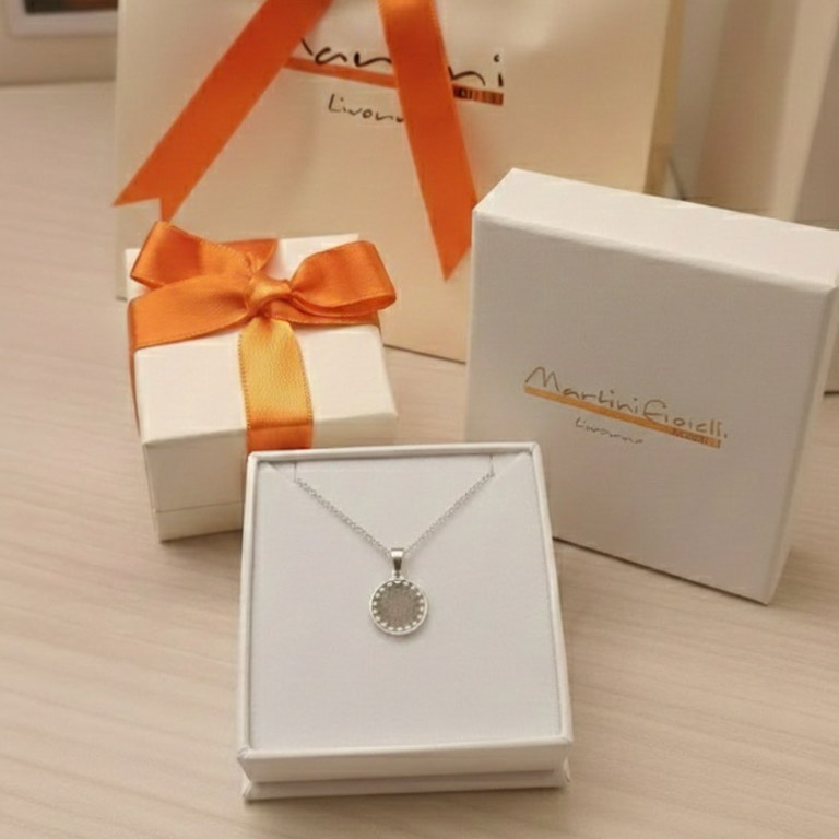 Questo pendente rotondo di 13 mm è decorato con piccoli cuori traforati lungo il bordo. Disponibile in oro Giallo, è stato creato con maestria artigianale nel nostro laboratorio orafo a Livorno. La superficie liscia e lucida è valorizzata da un’incisione laser precisa, rendendolo un pezzo unico e delicato. È un gioiello leggero, simbolico e versatile, perfetto per ogni stile e occasione.