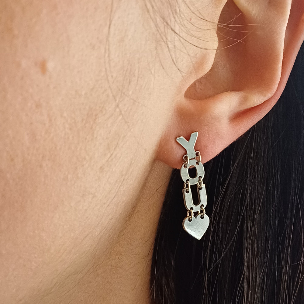 Gli orecchini sono pendenti e mobili, composti da lettere snodabili che formano la scritta "I LOVE YOU". Sono realizzati in argento liscio e brillante, con un design elegante e leggero. Grazie ai piccoli snodi tra le lettere, si muovono delicatamente ad ogni passo, creando un effetto dinamico e raffinato. Perfetti per chi ama gioielli con significato, esprimono un messaggio romantico e universale, da indossare con leggerezza e stile.