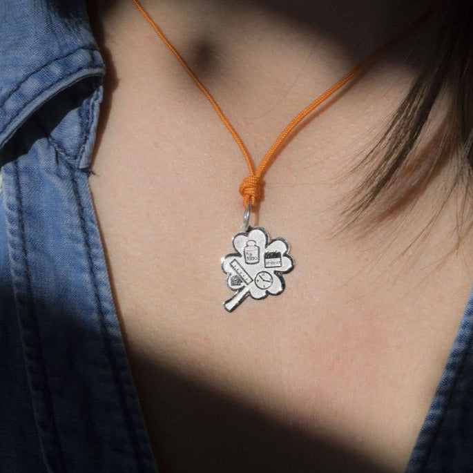 Pendente Quadrifoglio Nascita personalizzato in argento indossato con cordino arancio