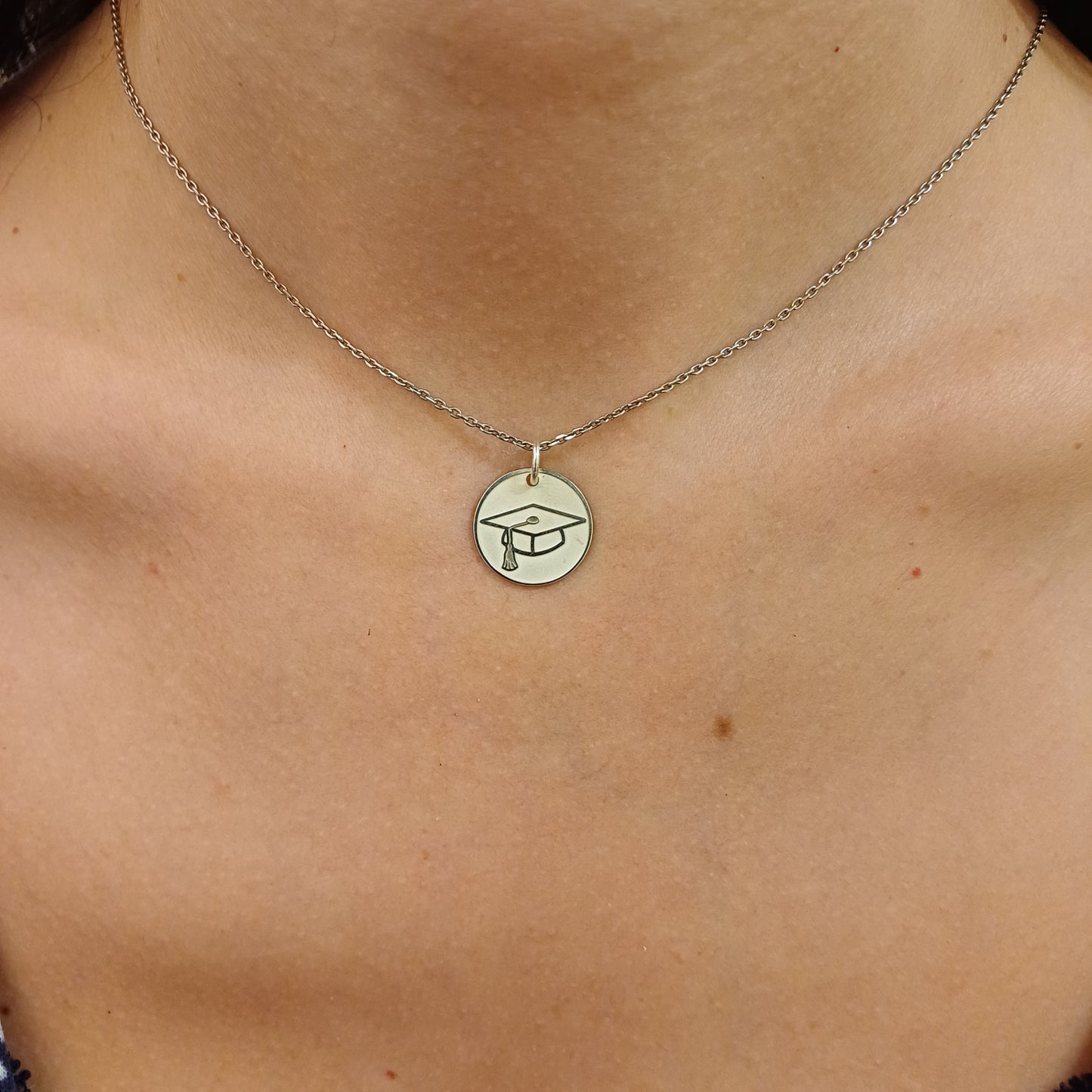 Pendente tondo da 15 mm, realizzato a mano, disponibile in oro giallo, oro bianco o argento 925. Sul fronte, una finitura satinata con cappello di laurea in rilievo; sul retro, superficie lucida perfetta per un'incisione personalizzata. Un gioiello simbolico, da regalare a chi ha raggiunto un importante traguardo accademico.
