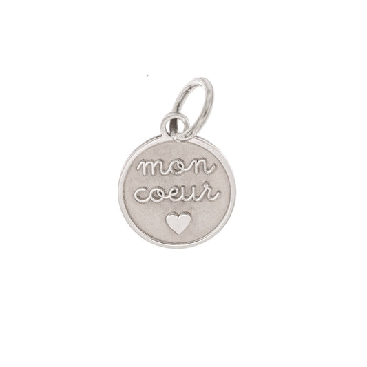 Ciondolo rotondo in argento 925 anallergico, diametro 10 mm. Sul davanti è incisa in rilievo la scritta “mon cœur”, con lettere dolci e rotonde, al centro di una superficie satinata. Sotto le parole è inciso un piccolo cuore pieno. Il bordo è sottile e liscio. Il retro è completamente piatto e può essere personalizzato con una breve incisione. Può essere usato come pendente per collana, bracciale o portachiavi. Leggero, delicato e simbolico.