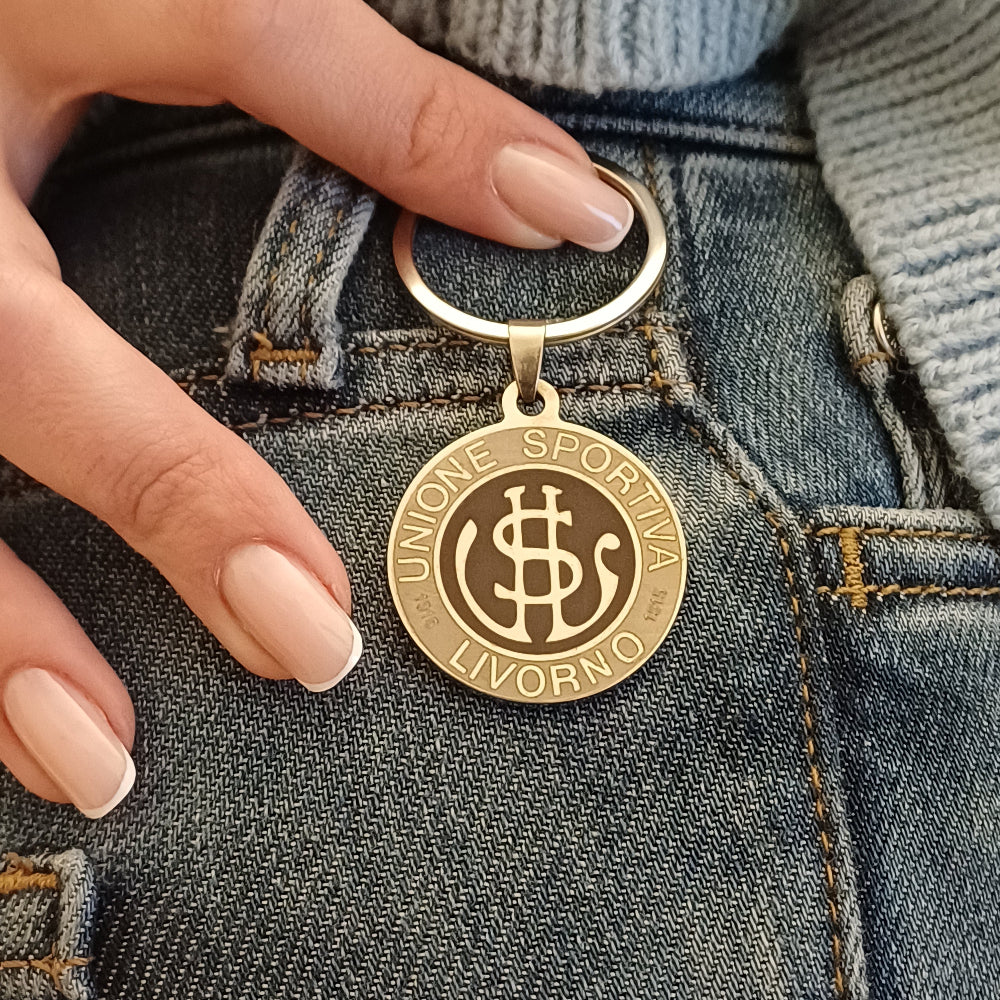 Questo portachiavi in acciaio dal diametro di 30 mm è robusto ma leggero, con una superficie liscia e fresca al tatto. Sul fronte, l’incisione laser del logo dell’U.S. Livorno crea un leggero rilievo percepibile con i polpastrelli, mentre il retro è personalizzabile con un’incisione su richiesta. Il metallo ha una finitura opaca ma riflettente, resistente all’usura. Pensato per i veri tifosi, è un oggetto elegante e simbolico, perfetto da portare sempre con sé.