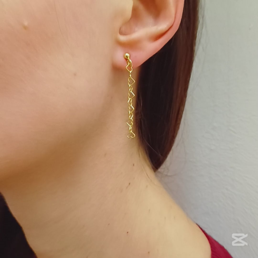 Questi orecchini pendenti sono realizzati in argento 925 nelle varianti Rodiato, Dorato e Ramato e presentano una catena leggera formata da piccoli cuori vuoti collegati tra loro. Il design è arioso e delicato, con una cascata sottile che ondeggia dolcemente con ogni movimento. La chiusura è a perno con farfallina, pratica e sicura. Il colore è un caldo oro giallo lucido, che riflette la luce in modo raffinato. Perfetti per chi ama i dettagli romantici e sofisticati.