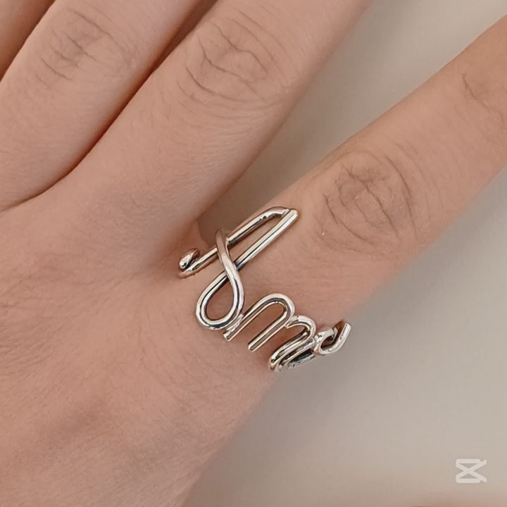 Immagina di accarezzare un filo d’argento liscio e brillante, che si snoda e si intreccia con eleganza fino a formare un nome. È un anello leggero e morbido al tatto, con curve armoniose e una struttura aperta, che segue dolcemente la forma del dito. Ogni lettera è parte di un unico filo, senza interruzioni, donando una sensazione di fluidità e continuità. Un gioiello su misura, pieno di emozione e personalità.