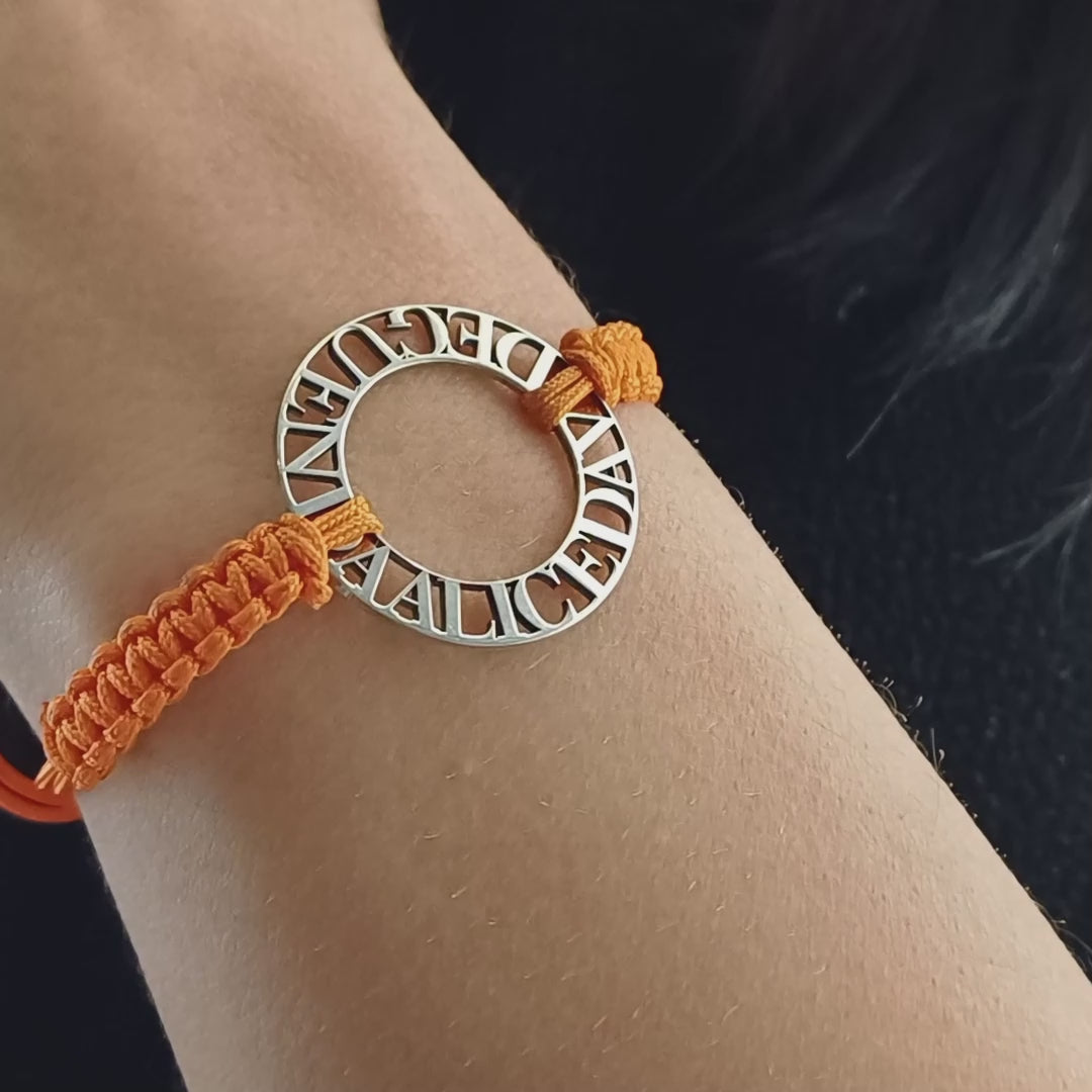 Immagina un cerchio liscio e leggero, con nomi traforati che emergono come piccole sculture tra il vuoto e la luce. Ogni lettera è incisa con precisione, creando un contrasto tra il metallo freddo e il calore del cordino intrecciato a mano, morbido e avvolgente sul polso. La superficie è liscia, con bordi definiti ma delicati al tatto. Questo bracciale personalizzato è un abbraccio in argento, con parole che parlano di affetti, ricordi e connessioni profonde.