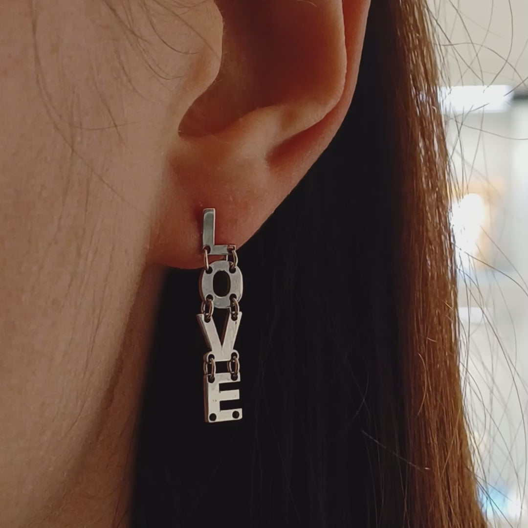 Gli orecchini sono pendenti e mobili, composti da lettere snodabili che formano la scritta "I LOVE YOU". Sono realizzati in argento liscio e brillante, con un design elegante e leggero. Grazie ai piccoli snodi tra le lettere, si muovono delicatamente ad ogni passo, creando un effetto dinamico e raffinato. Perfetti per chi ama gioielli con significato, esprimono un messaggio romantico e universale, da indossare con leggerezza e stile.