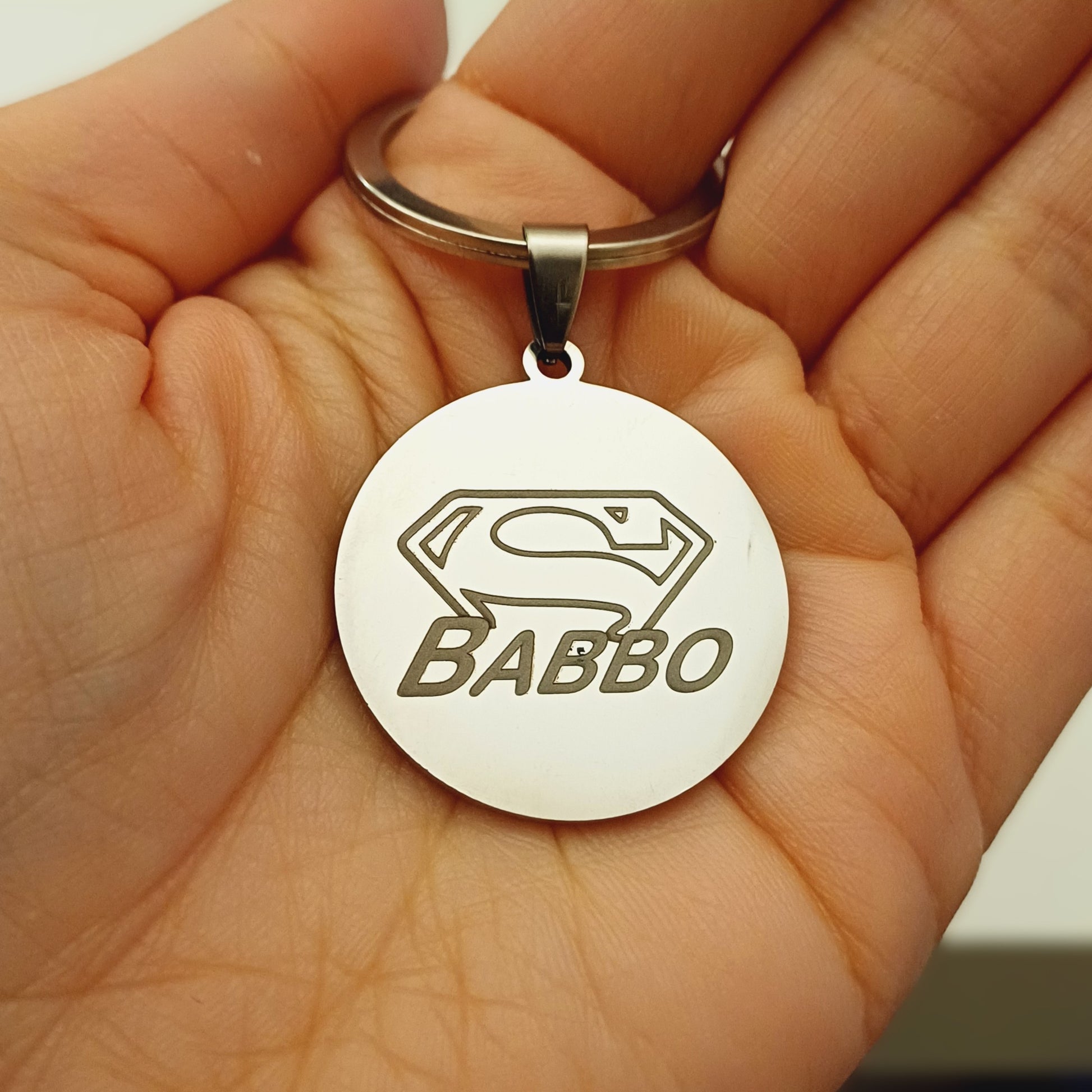 Un portachiavi rotondo, dal diametro di 30 mm, realizzato in acciaio resistente e piacevolmente liscio al tatto. Sulla sua superficie è incisa a laser un’immagine speciale, dedicata alla Festa del Papà. L’incisione è nitida e percettibile sotto le dita, creando un effetto leggermente ruvido che contrasta con la lucentezza del metallo. Solido ma leggero, è perfetto per accompagnare ogni giorno il papà che lo riceverà in dono. Personalizzabile con un nome o una frase speciale.