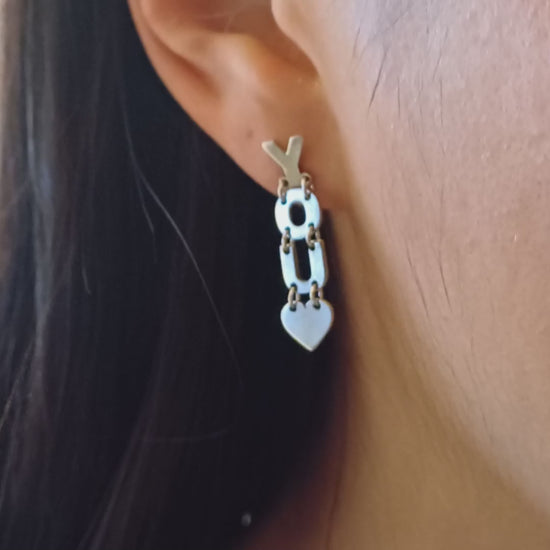 Gli orecchini sono pendenti e mobili, composti da lettere snodabili che formano la scritta "I LOVE YOU". Sono realizzati in argento liscio e brillante, con un design elegante e leggero. Grazie ai piccoli snodi tra le lettere, si muovono delicatamente ad ogni passo, creando un effetto dinamico e raffinato. Perfetti per chi ama gioielli con significato, esprimono un messaggio romantico e universale, da indossare con leggerezza e stile.
