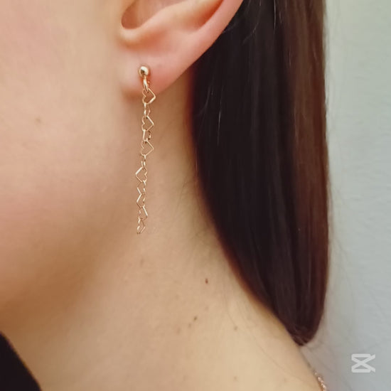 Questi orecchini pendenti sono realizzati in argento 925 nelle varianti Rodiato, Dorato e Ramato e presentano una catena leggera formata da piccoli cuori vuoti collegati tra loro. Il design è arioso e delicato, con una cascata sottile che ondeggia dolcemente con ogni movimento. La chiusura è a perno con farfallina, pratica e sicura. Il colore è un caldo oro giallo lucido, che riflette la luce in modo raffinato. Perfetti per chi ama i dettagli romantici e sofisticati.