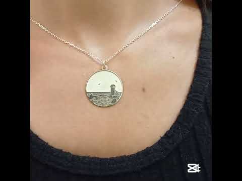 Questa è una medaglia in argento 925, rotonda e piatta, con un diametro di circa 20 mm. Sulla superficie è incisa la Torre di Calafuria, un faro storico situato sulla costa di Livorno. La torre è rappresentata in rilievo, con dettagli che mostrano il paesaggio circostante, come il mare e la scogliera. È un pezzo elegante e simbolico, pensato per celebrare un luogo iconico. La medaglia è dotata di un piccolo anello sulla parte superiore, che ne consente l'uso come ciondolo.