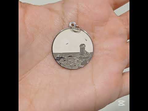 Questa è una medaglia in argento 925, rotonda e piatta, con un diametro di circa 20 mm. Sulla superficie è incisa la Torre di Calafuria, un faro storico situato sulla costa di Livorno. La torre è rappresentata in rilievo, con dettagli che mostrano il paesaggio circostante, come il mare e la scogliera. È un pezzo elegante e simbolico, pensato per celebrare un luogo iconico. La medaglia è dotata di un piccolo anello sulla parte superiore, che ne consente l'uso come ciondolo.